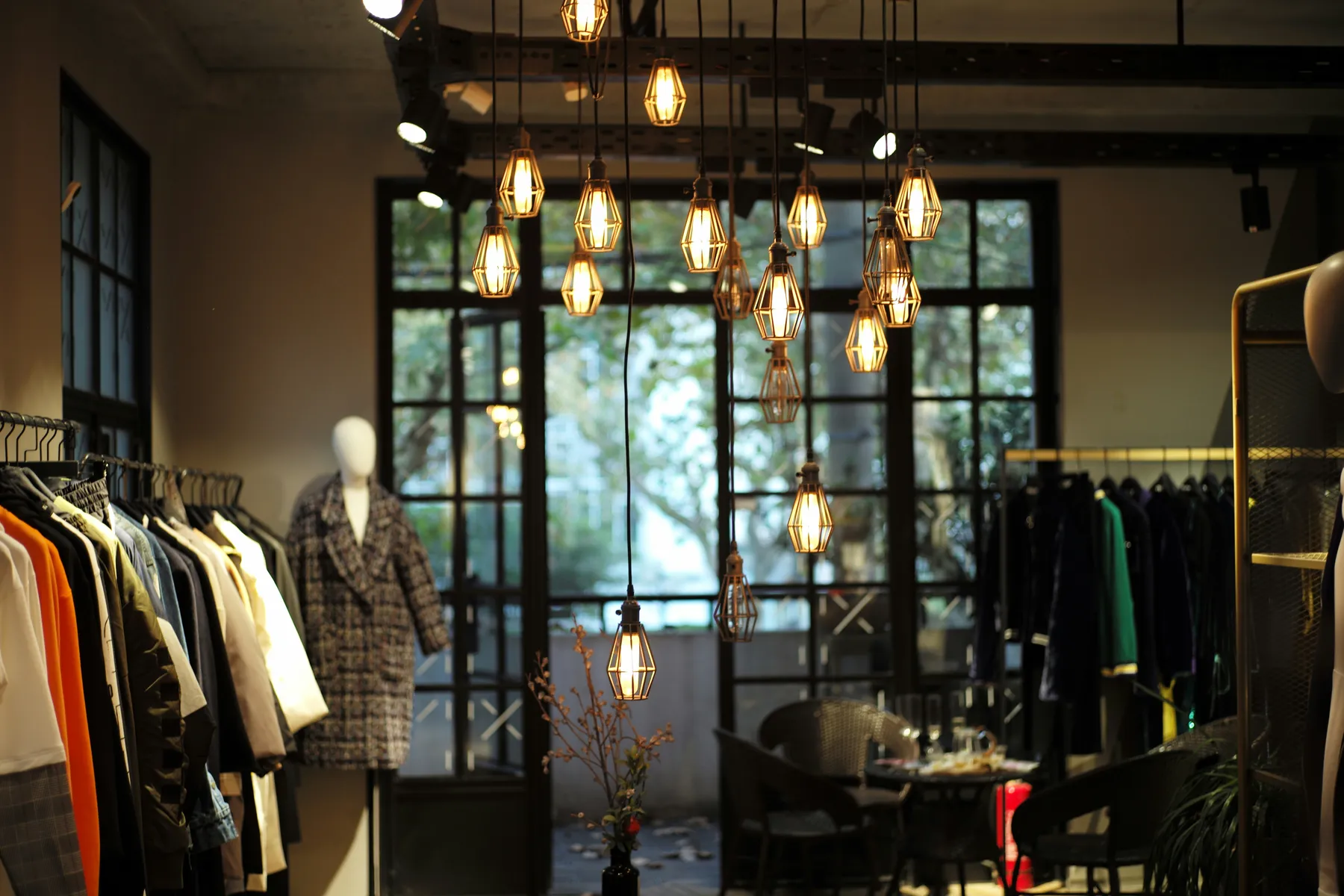Stilvolles Boutique-Interieur mit modernen Hängelampen, Schaufensterpuppen und Kleiderständern mit modischer Kleidung.
